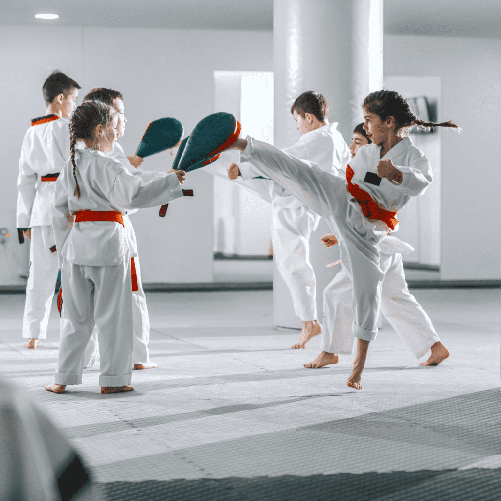 enfants pratiquant du taekwondo avec des raquettes en donnant des coups de pieds